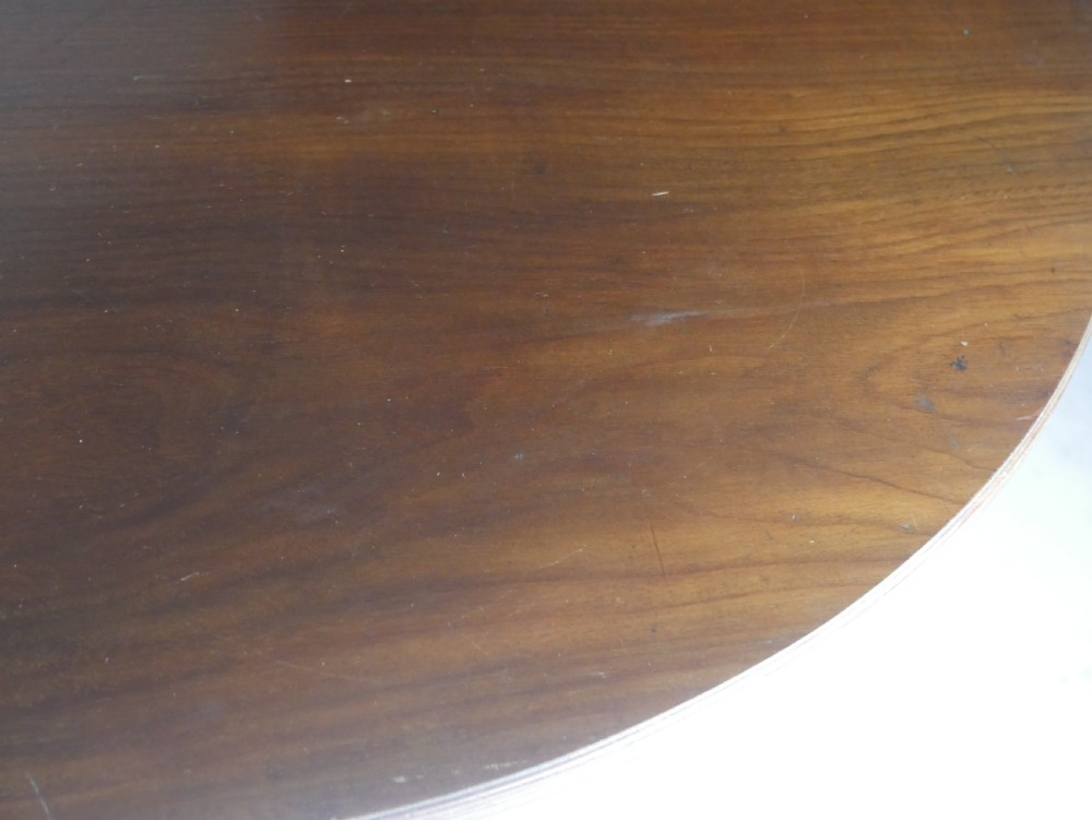 An antique mahogany drop-leaf dining table with reeded legs set on brass castors, shown fully extended. View III