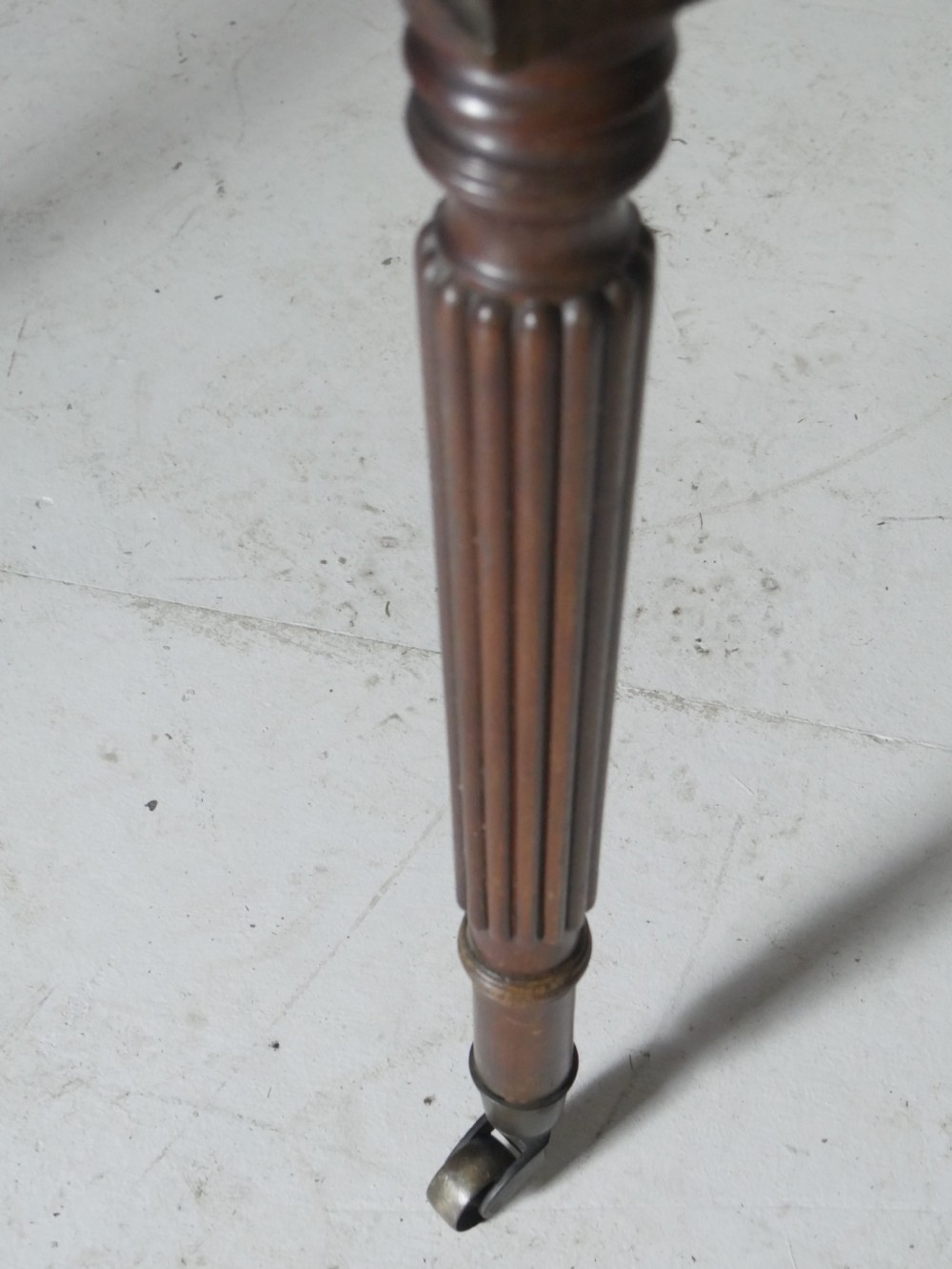 An antique mahogany drop-leaf dining table with reeded legs set on brass castors, shown fully extended. View XI