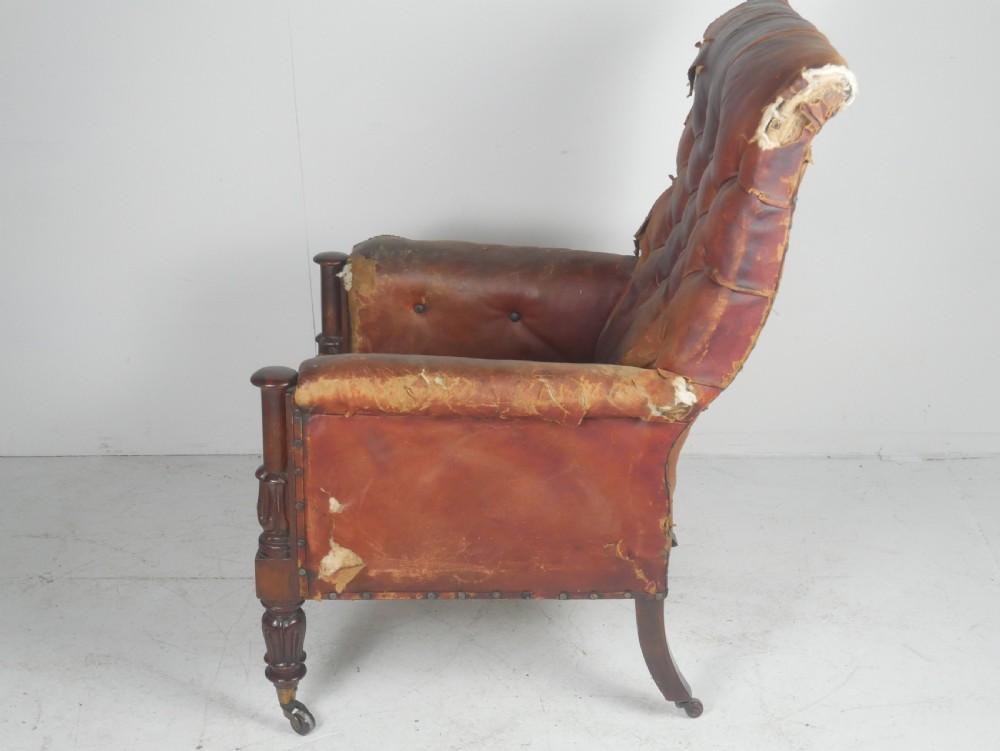 A distressed Regency library armchair with deep-buttoned red leather upholstery, turned mahogany front legs, and brass castors. View VII