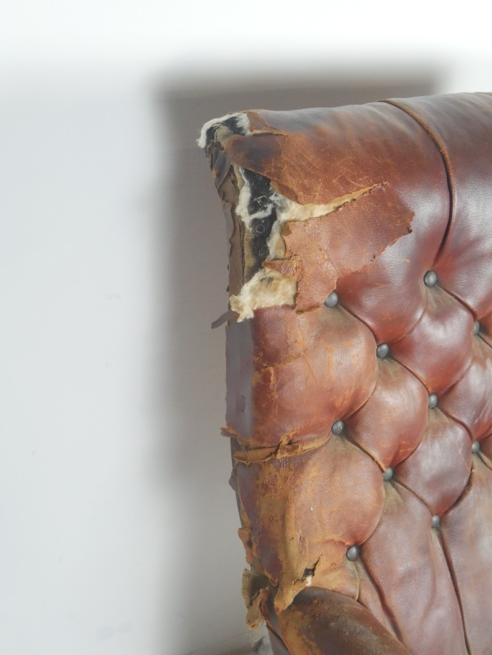 A distressed Regency library armchair with deep-buttoned red leather upholstery, turned mahogany front legs, and brass castors. View VIII