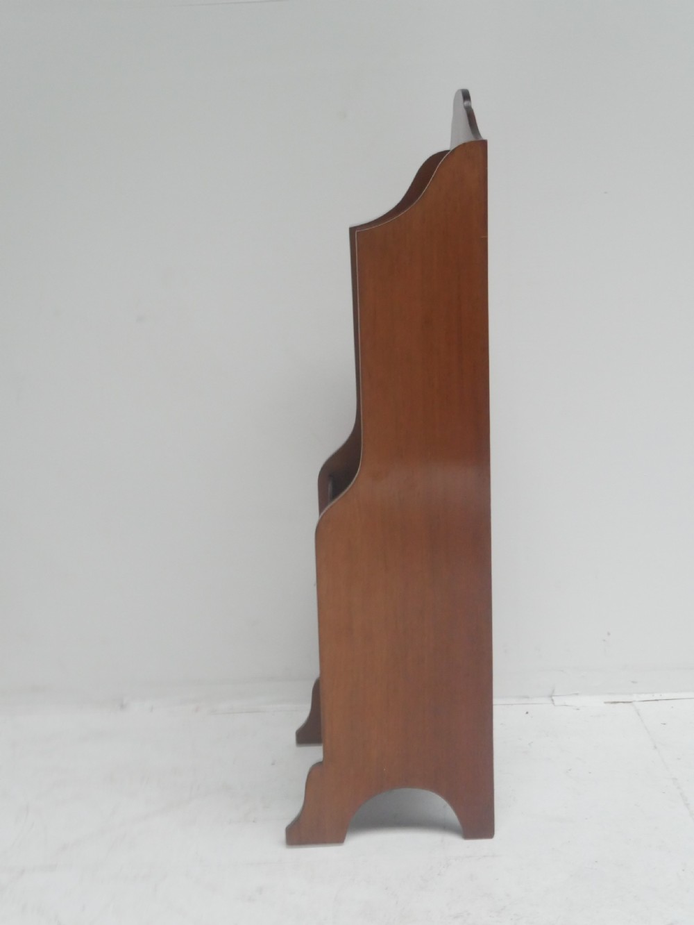 A freestanding three-tiered mahogany magazine rack featuring curved cutout fronts, an integrated top handle, and inlaid stringing borders on splayed feet. View II