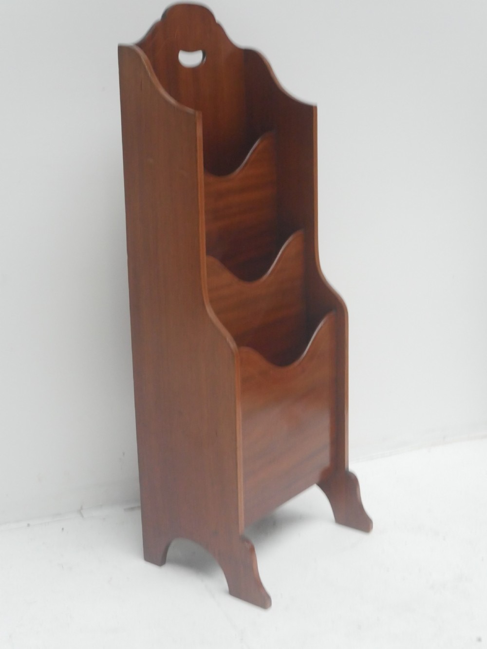 A freestanding three-tiered mahogany magazine rack featuring curved cutout fronts, an integrated top handle, and inlaid stringing borders on splayed feet. View XI