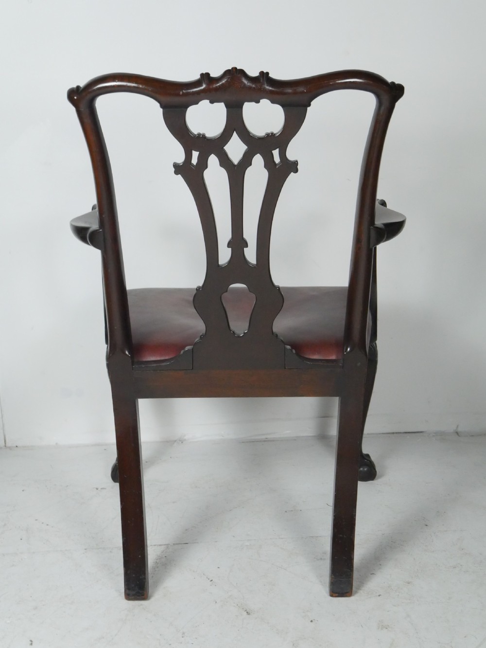 A pair of 19th-century Chippendale style mahogany armchairs featuring pierced back splats, reddish-brown leather seats with studding, and cabriole legs with ball-and-claw feet. View II