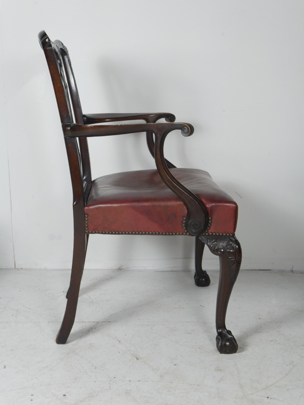 A pair of 19th-century Chippendale style mahogany armchairs featuring pierced back splats, reddish-brown leather seats with studding, and cabriole legs with ball-and-claw feet. View IV