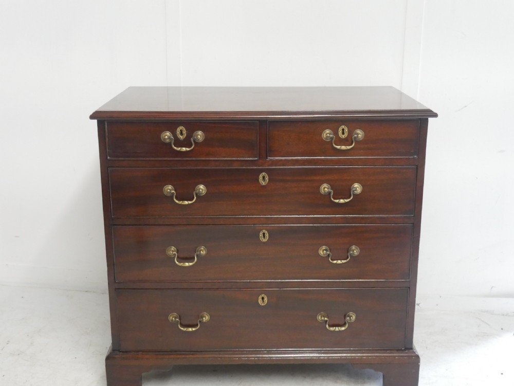 A Georgian mahogany chest of drawers featuring a two-over-three drawer layout, brass swan-neck handles, and bracket feet. View II