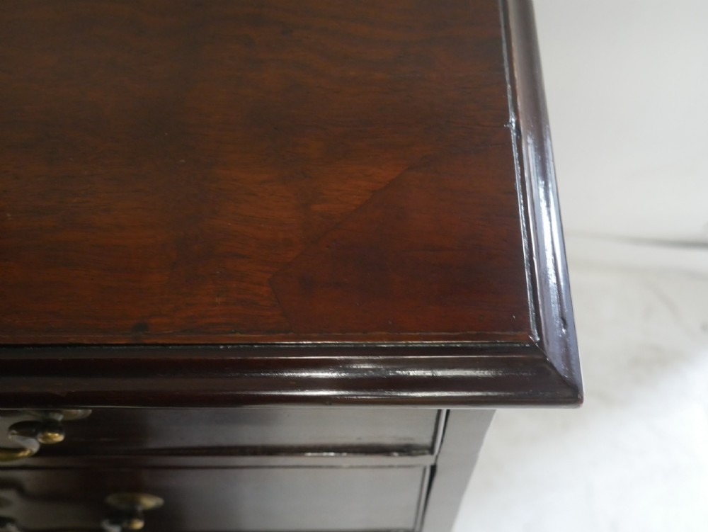 A Georgian mahogany chest of drawers featuring a two-over-three drawer layout, brass swan-neck handles, and bracket feet. View III