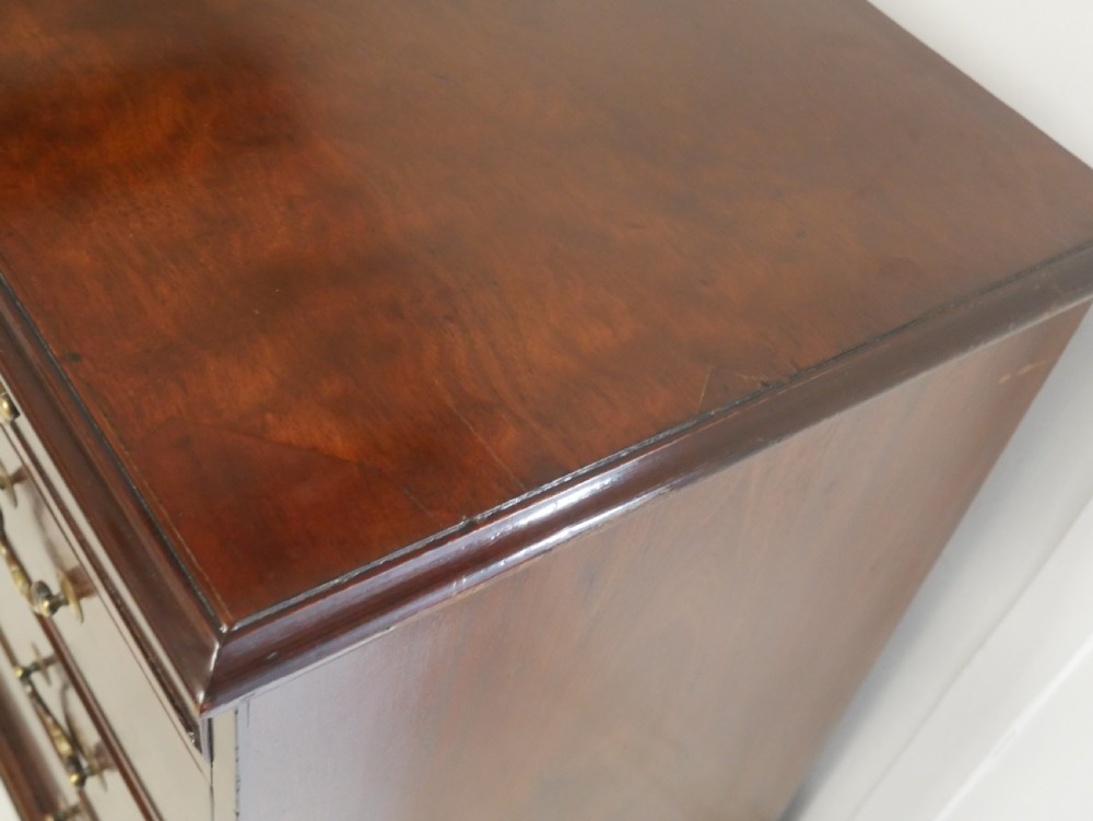 A Georgian mahogany chest of drawers featuring a two-over-three drawer layout, brass swan-neck handles, and bracket feet. View VI