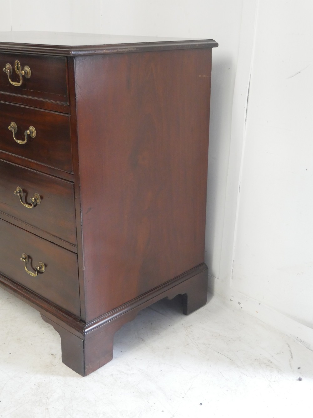 A Georgian mahogany chest of drawers featuring a two-over-three drawer layout, brass swan-neck handles, and bracket feet. View VII