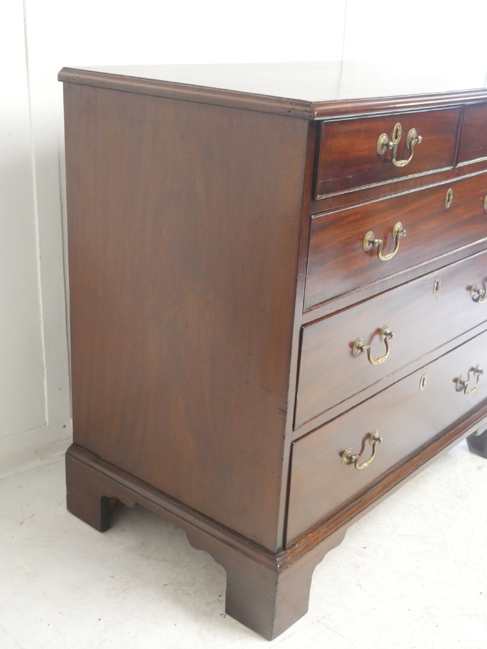 A Georgian mahogany chest of drawers featuring a two-over-three drawer layout, brass swan-neck handles, and bracket feet. View VIII