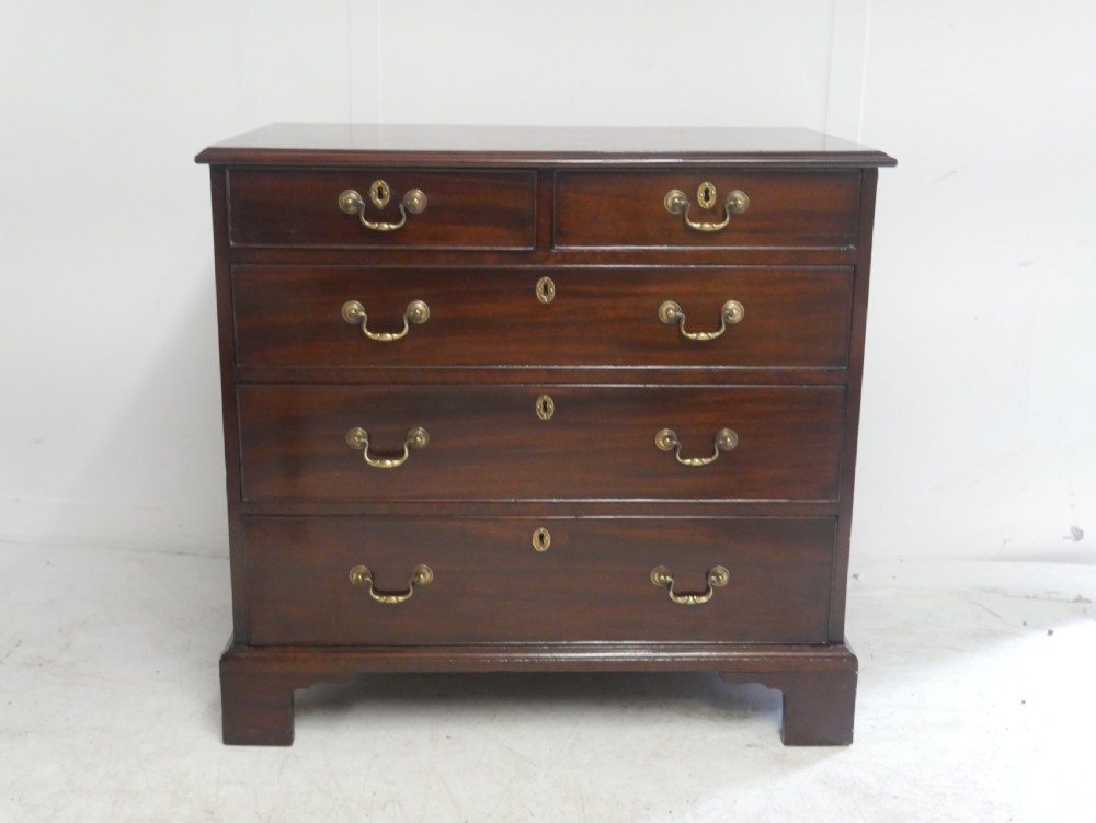 A Georgian mahogany chest of drawers featuring a two-over-three drawer layout, brass swan-neck handles, and bracket feet. View XIV