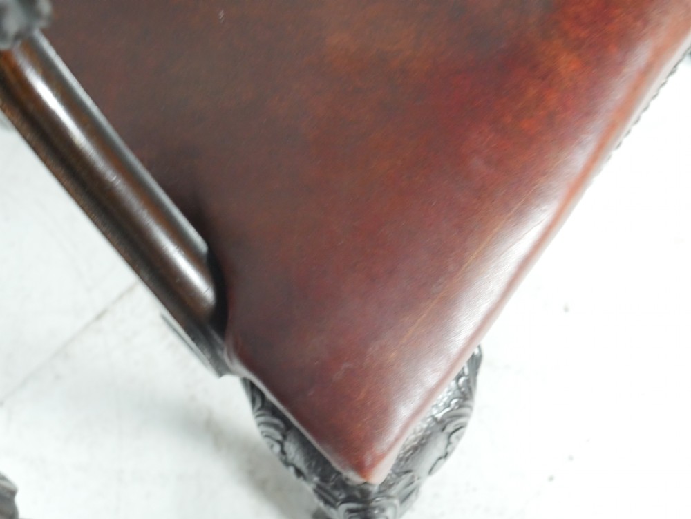 A pair of 19th-century Chippendale style mahogany armchairs featuring pierced back splats, reddish-brown leather seats with studding, and cabriole legs with ball-and-claw feet. View V