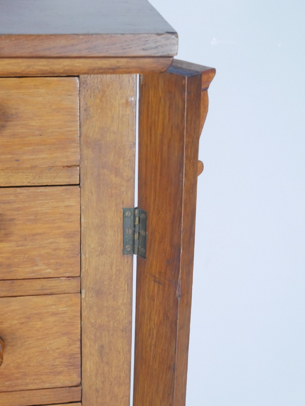 A tall Victorian oak Wellington chest featuring seven drawers with turned wooden knob handles, carved corbels at the top corners, and a locking side flap. View IV