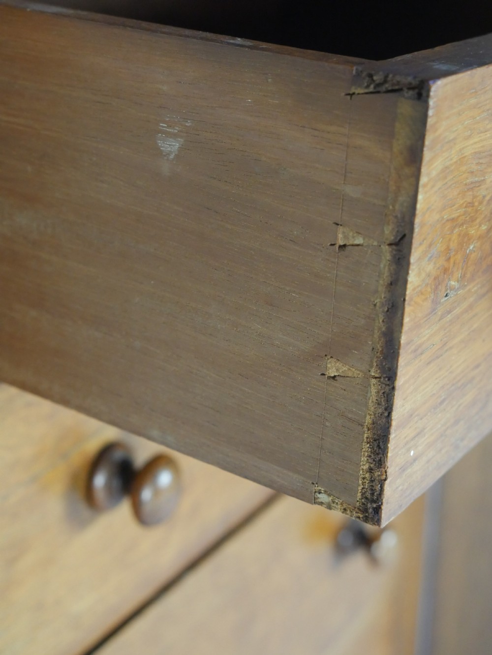 A tall Victorian oak Wellington chest featuring seven drawers with turned wooden knob handles, carved corbels at the top corners, and a locking side flap. View V