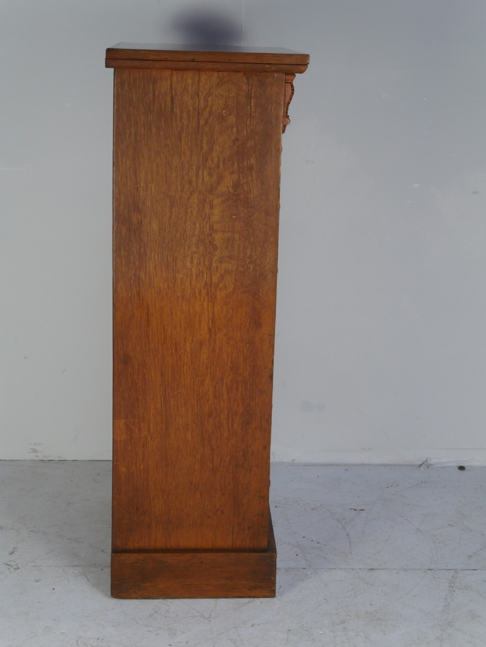 A tall Victorian oak Wellington chest featuring seven drawers with turned wooden knob handles, carved corbels at the top corners, and a locking side flap. View VIII
