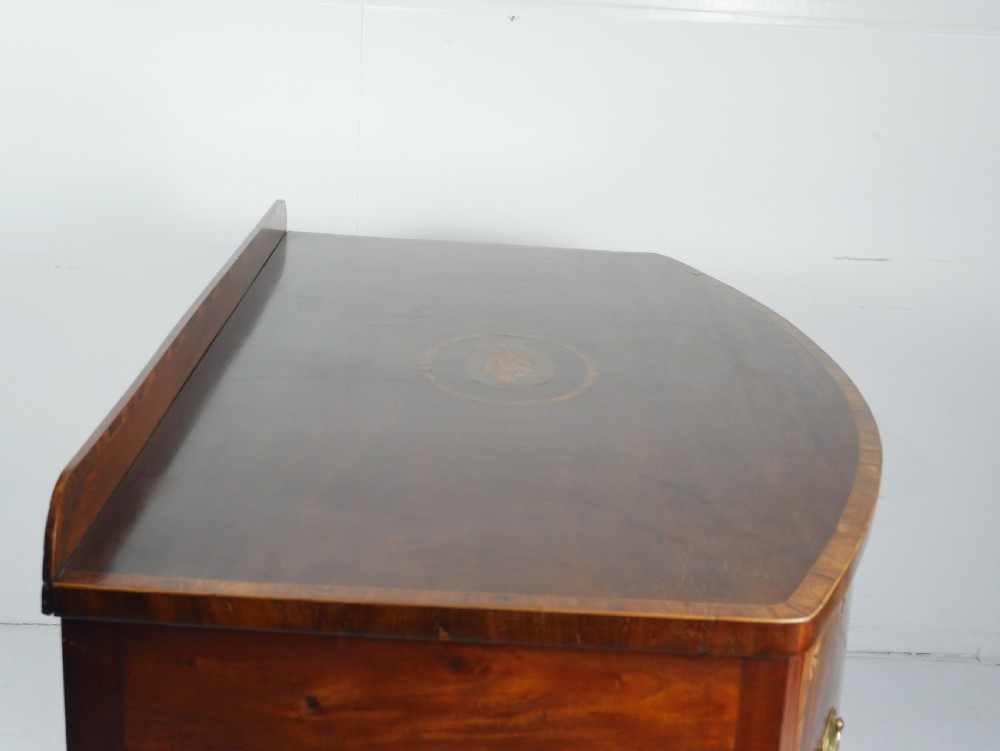 A Georgian bow-front mahogany sideboard featuring satinwood inlays, brass oval handles, and square tapered legs. View II