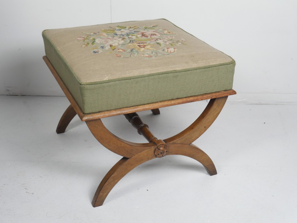 A Regency period rosewood X-frame stool with a turned stretcher bar and a square upholstered top featuring floral needlework set within a green border. View II