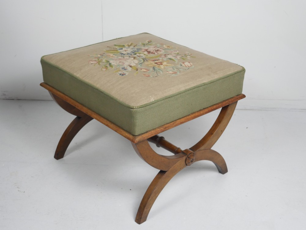 A Regency period rosewood X-frame stool with a turned stretcher bar and a square upholstered top featuring floral needlework set within a green border. View XIII