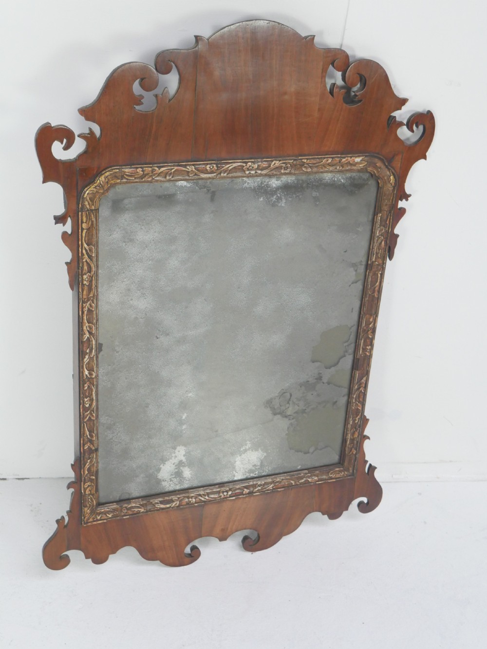 A Georgian mahogany wall mirror featuring a scroll-carved fretwork frame with an inner gilded slip border. View IV