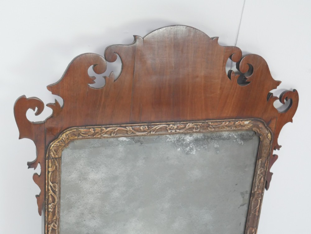 A Georgian mahogany wall mirror featuring a scroll-carved fretwork frame with an inner gilded slip border. View V