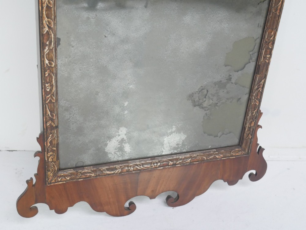 A Georgian mahogany wall mirror featuring a scroll-carved fretwork frame with an inner gilded slip border. View VI