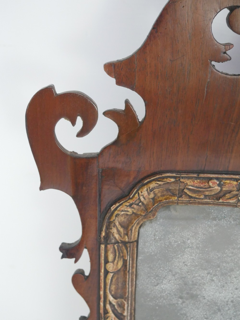 A Georgian mahogany wall mirror featuring a scroll-carved fretwork frame with an inner gilded slip border. View VIII