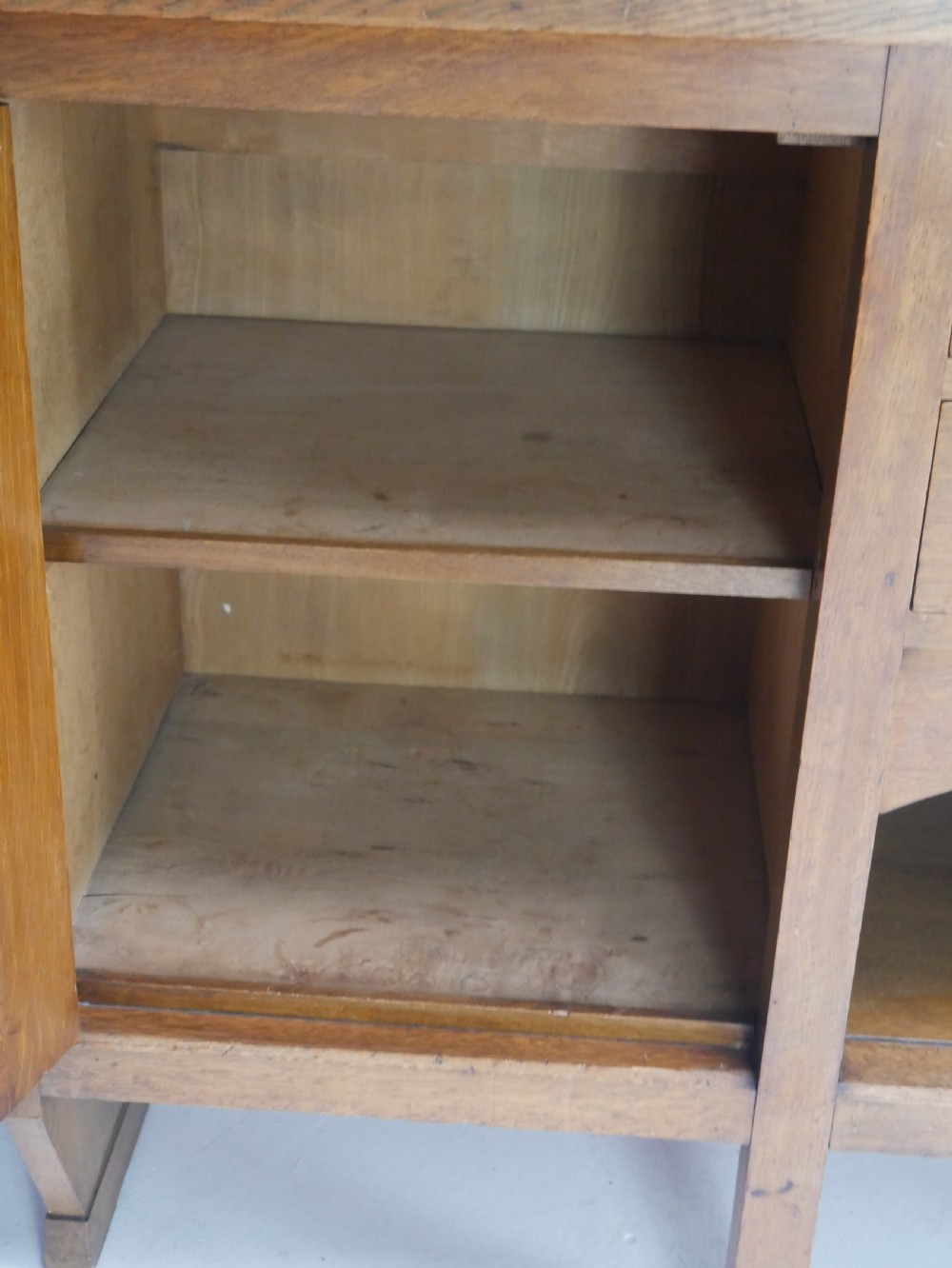 An Arts and Crafts solid oak dresser featuring an upper section with a central mirror flanked by two small cupboards, set above a lower sideboard base with drawers and side doors. View V