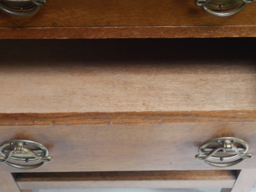 An Arts and Crafts solid oak dresser featuring an upper section with a central mirror flanked by two small cupboards, set above a lower sideboard base with drawers and side doors. View VII