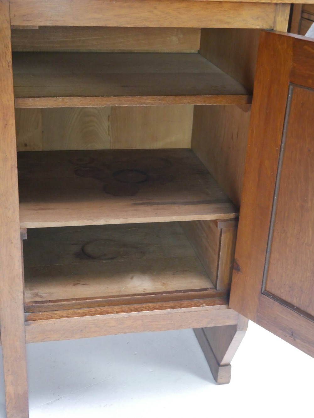 An Arts and Crafts solid oak dresser featuring an upper section with a central mirror flanked by two small cupboards, set above a lower sideboard base with drawers and side doors. View VIII