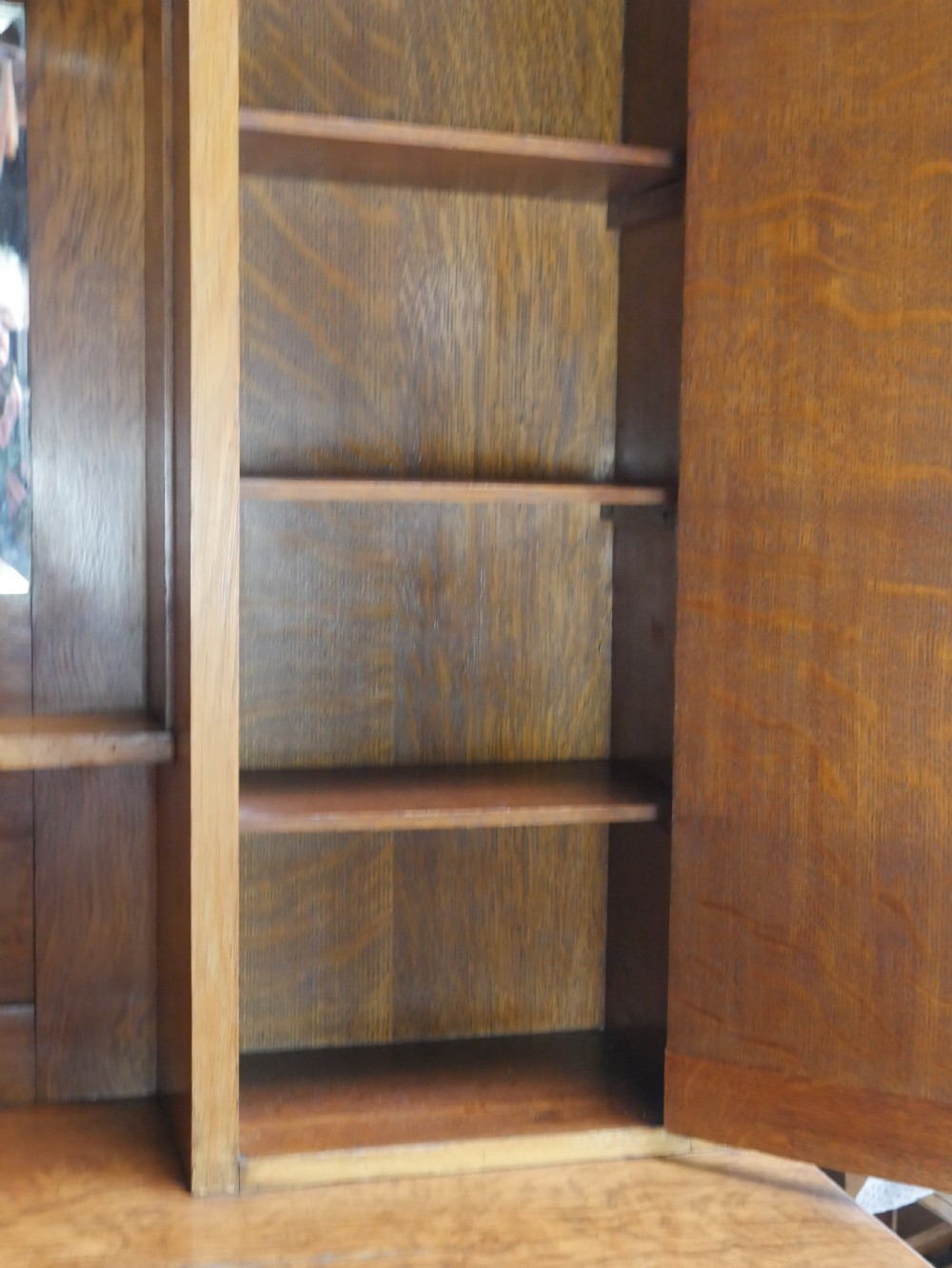 An Arts and Crafts solid oak dresser featuring an upper section with a central mirror flanked by two small cupboards, set above a lower sideboard base with drawers and side doors. View X