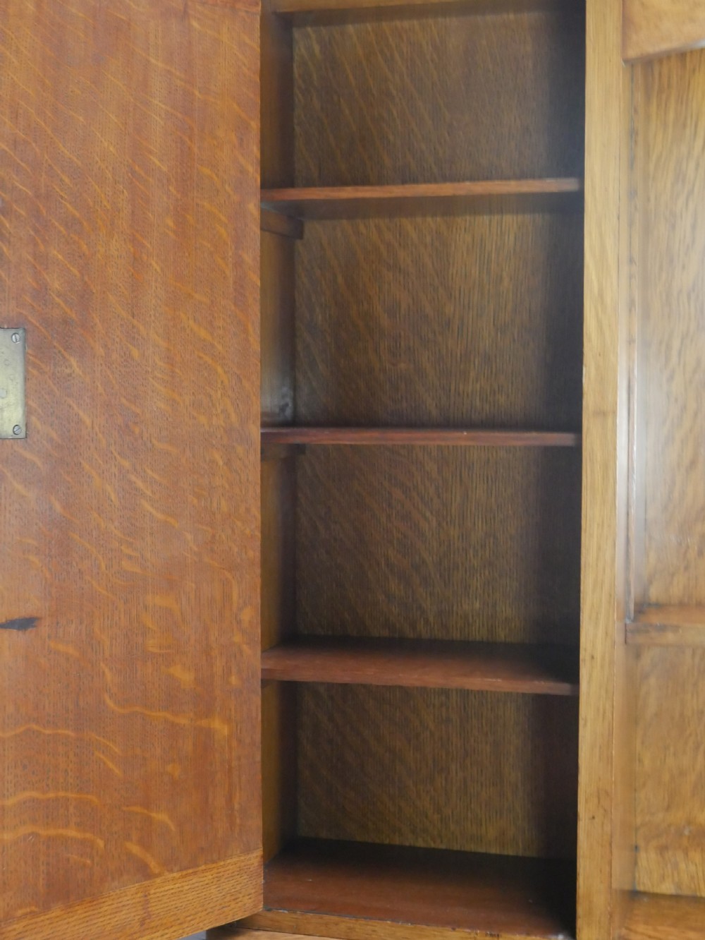 An Arts and Crafts solid oak dresser featuring an upper section with a central mirror flanked by two small cupboards, set above a lower sideboard base with drawers and side doors. View XI