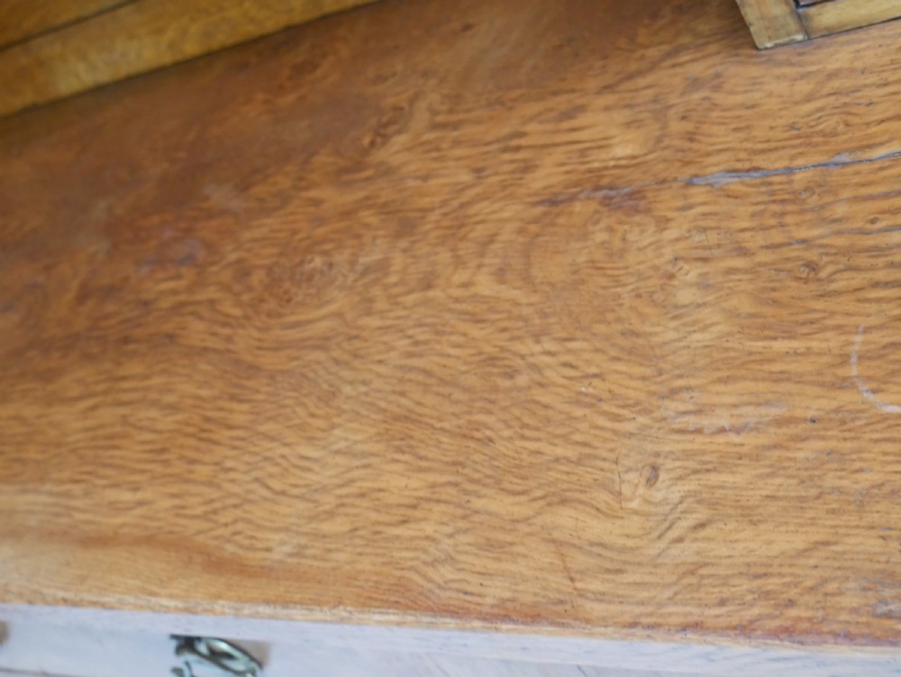 An Arts and Crafts solid oak dresser featuring an upper section with a central mirror flanked by two small cupboards, set above a lower sideboard base with drawers and side doors. View XV