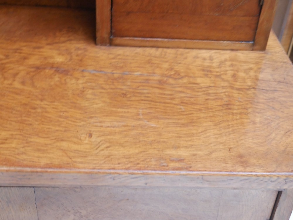 An Arts and Crafts solid oak dresser featuring an upper section with a central mirror flanked by two small cupboards, set above a lower sideboard base with drawers and side doors. View XVIII