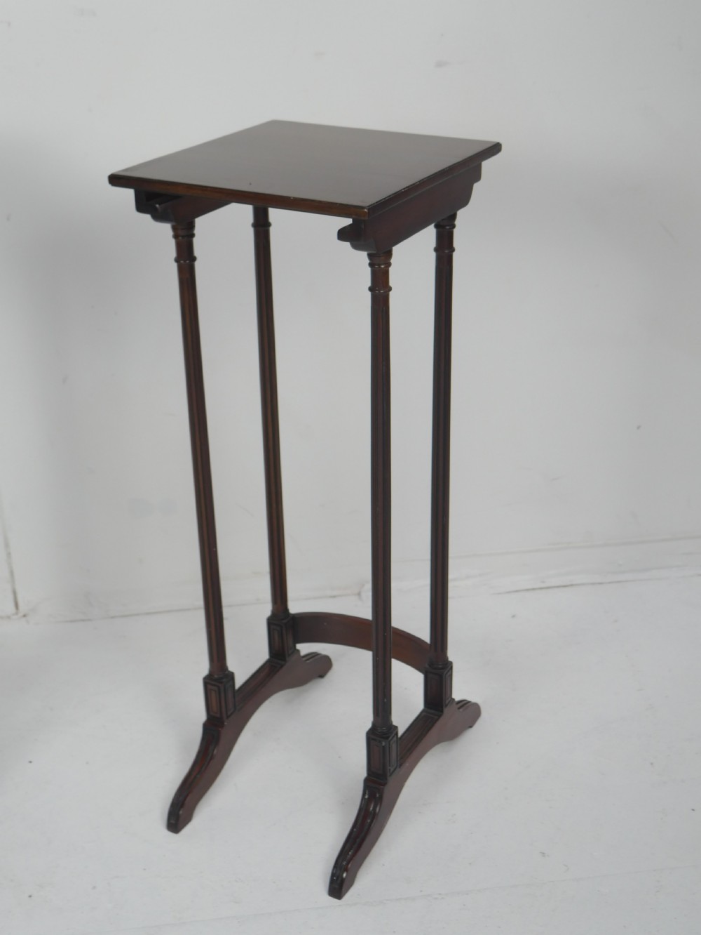 A set of four dark mahogany rectangular nesting tables with slender reeded legs and curved stretchers stacked together. View II