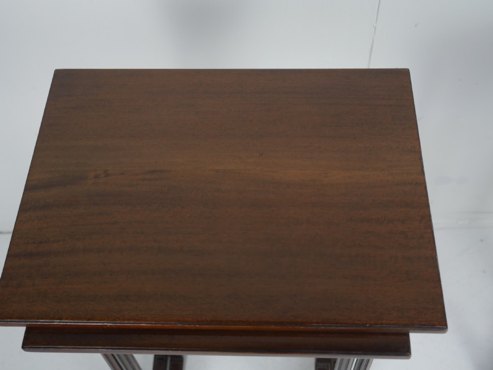 A set of four dark mahogany rectangular nesting tables with slender reeded legs and curved stretchers stacked together. View V