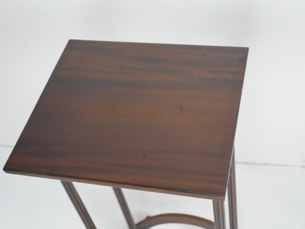 A set of four dark mahogany rectangular nesting tables with slender reeded legs and curved stretchers stacked together. View VI