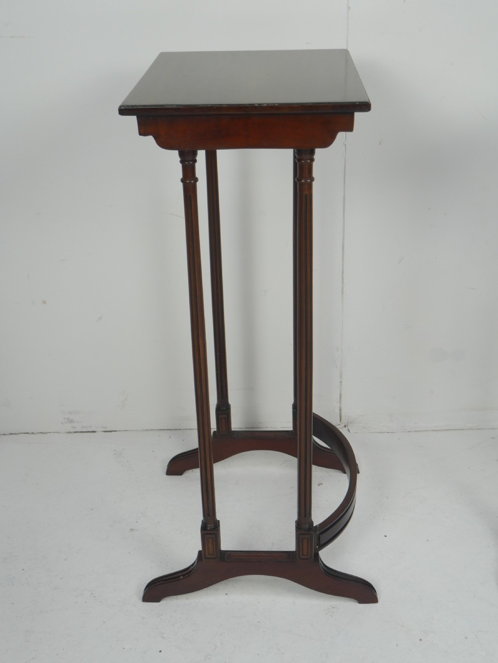 A set of four dark mahogany rectangular nesting tables with slender reeded legs and curved stretchers stacked together. View VII