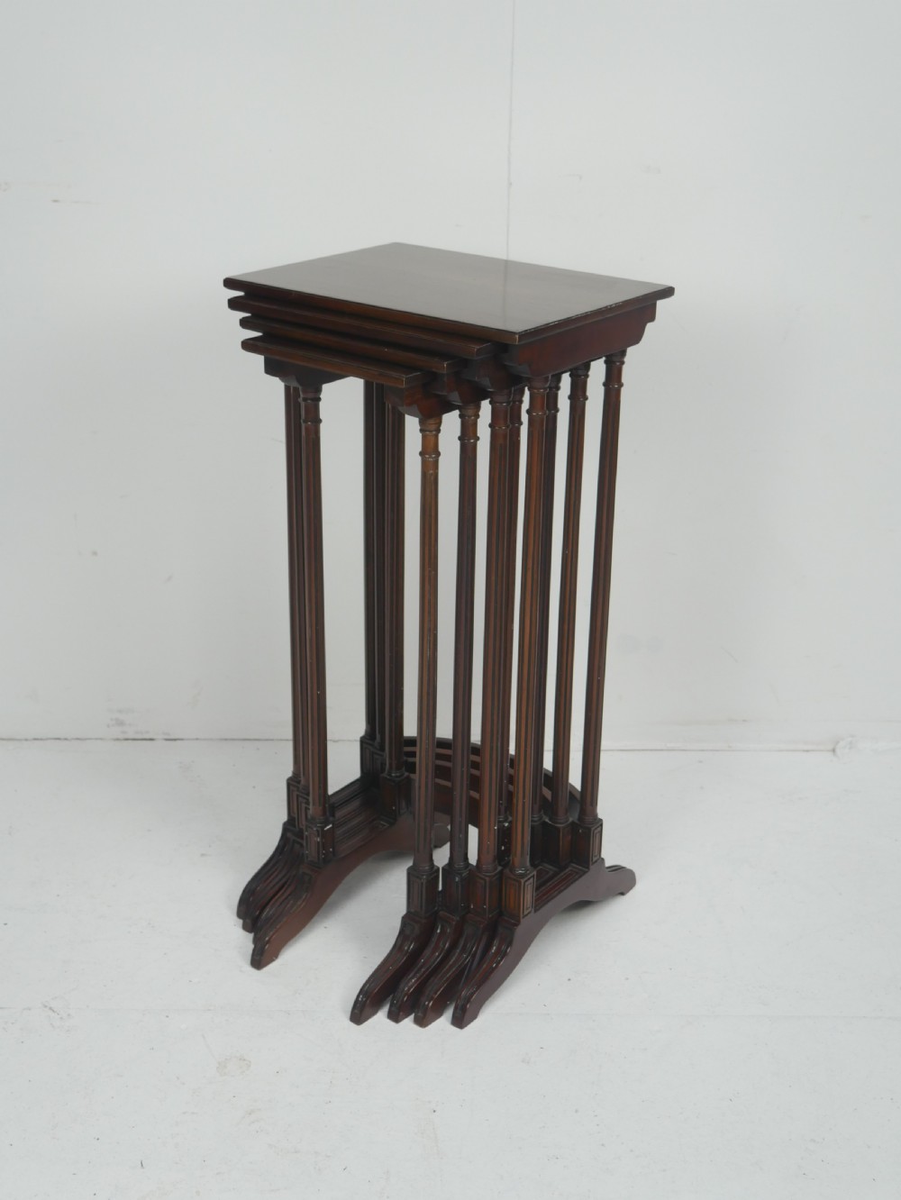 A set of four dark mahogany rectangular nesting tables with slender reeded legs and curved stretchers stacked together. View VIII