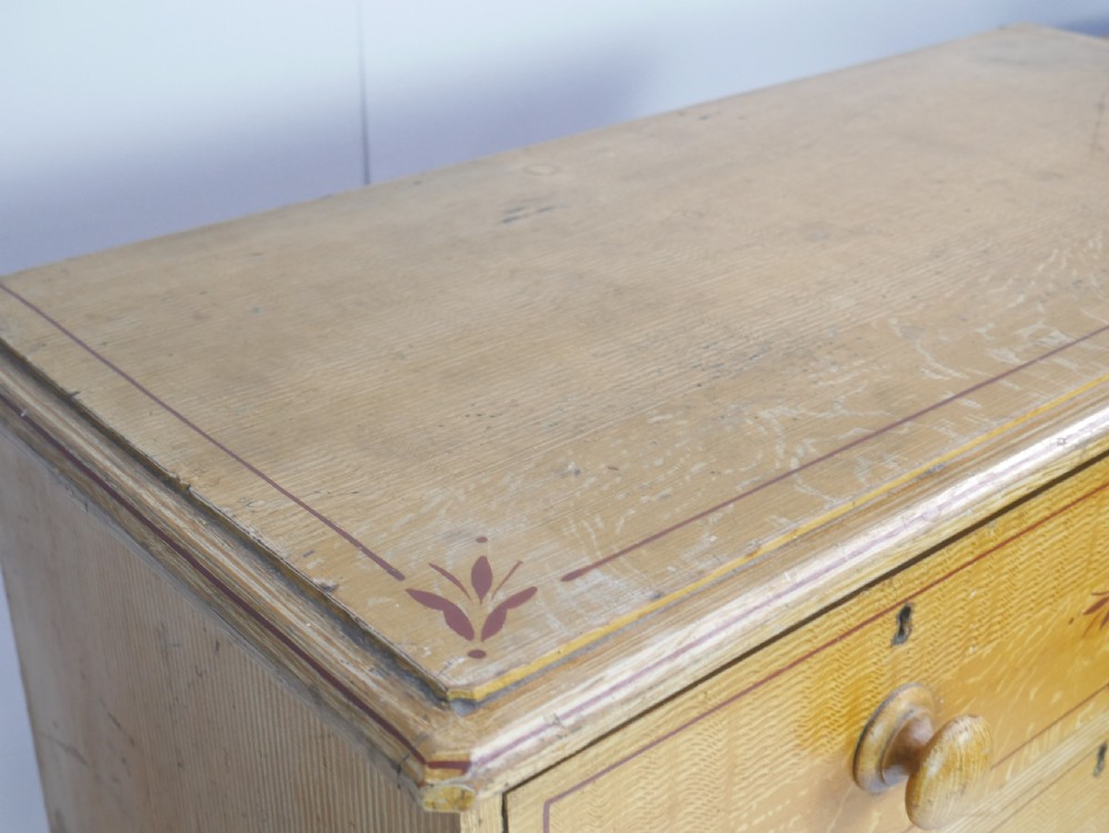 An antique Victorian painted pine chest featuring two short over two long drawers with faux graining, red line borders, wooden knobs, and turned feet. View VII