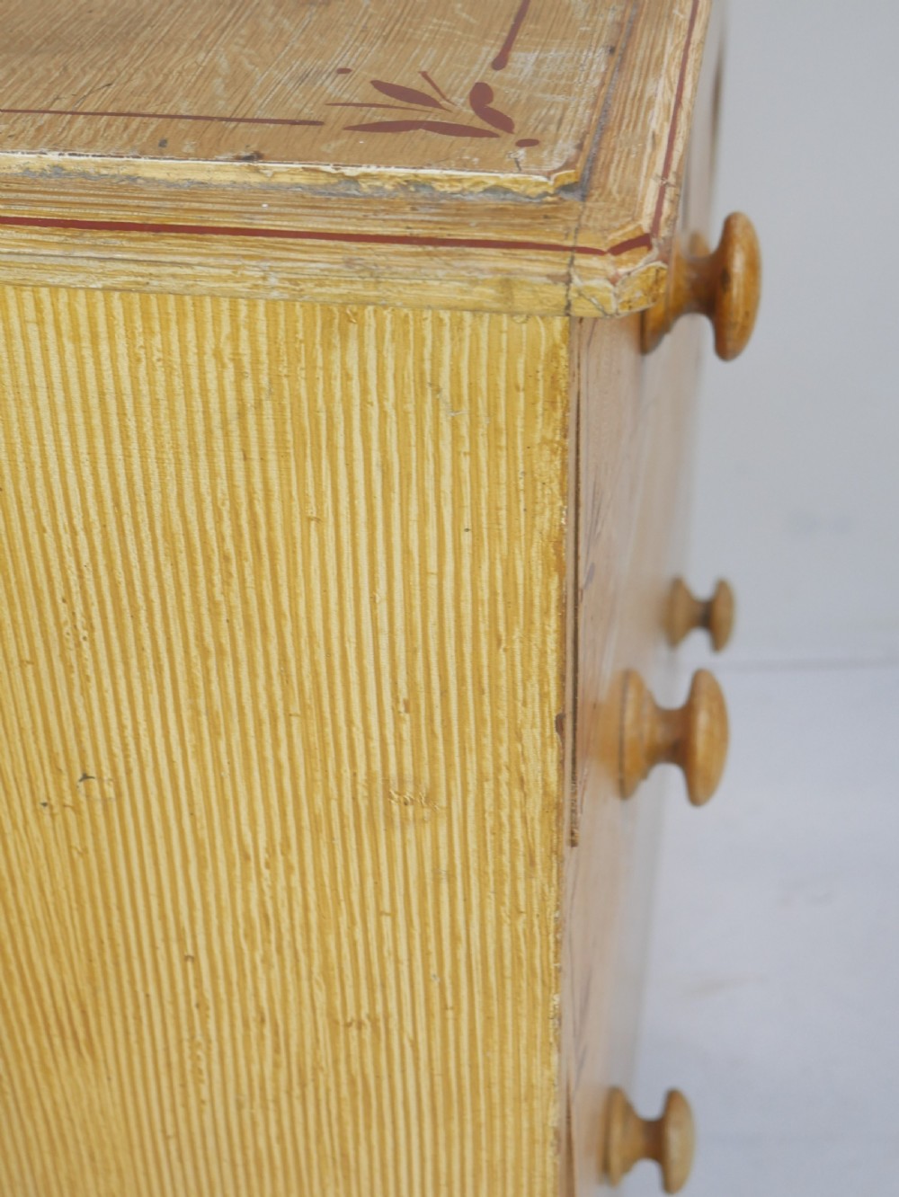 An antique Victorian painted pine chest featuring two short over two long drawers with faux graining, red line borders, wooden knobs, and turned feet. View XIV