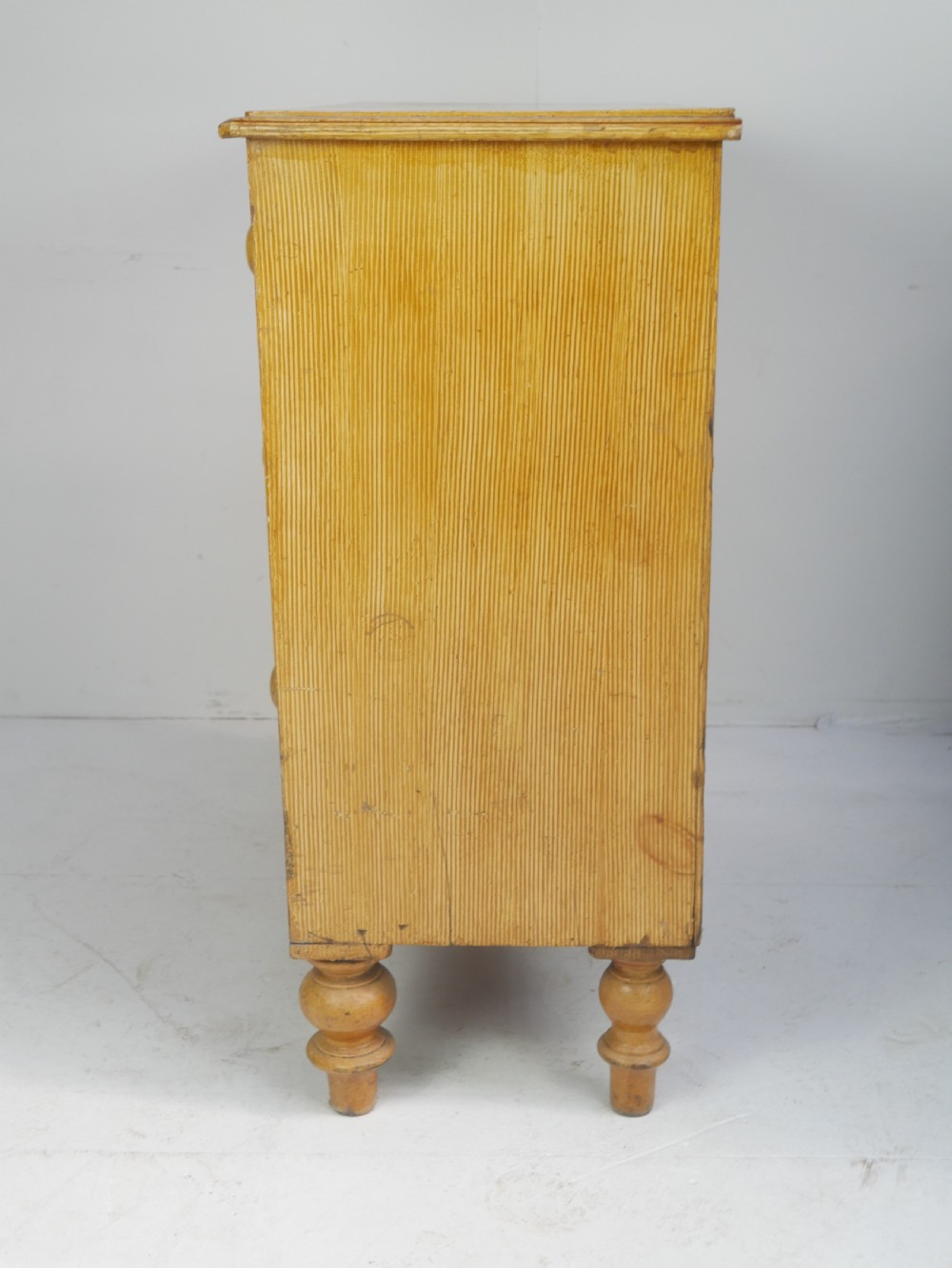 An antique Victorian painted pine chest featuring two short over two long drawers with faux graining, red line borders, wooden knobs, and turned feet. View XV