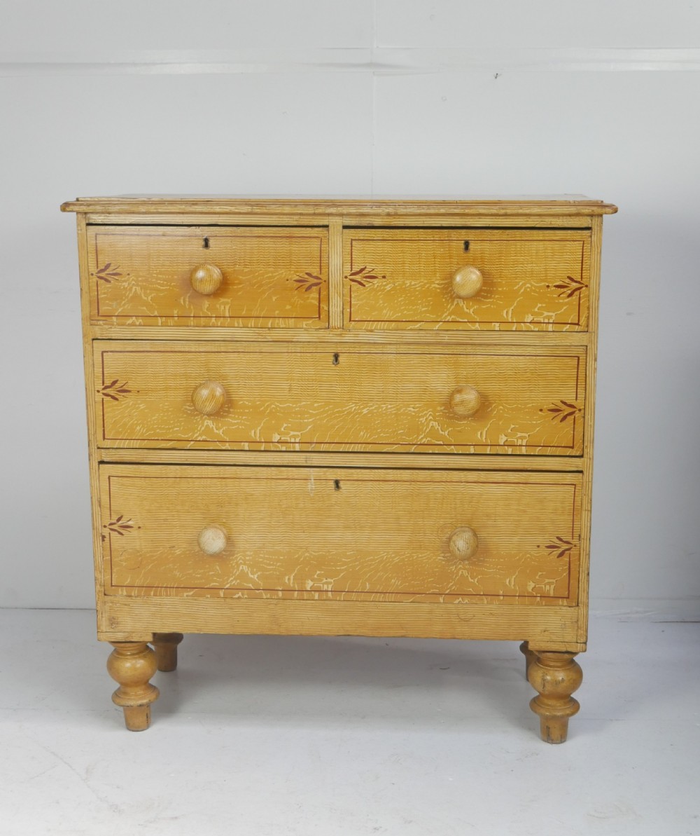 An antique Victorian painted pine chest featuring two short over two long drawers with faux graining, red line borders, wooden knobs, and turned feet. View XVII