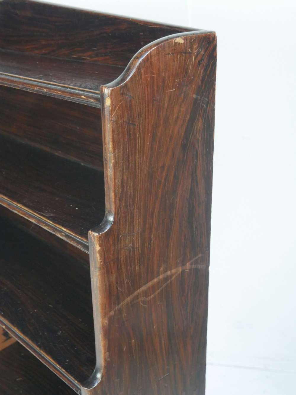 A dark brown 19th-century waterfall bookcase featuring four open stepped shelves, side profile cutouts, and turned legs. View II