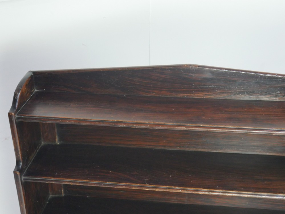 A dark brown 19th-century waterfall bookcase featuring four open stepped shelves, side profile cutouts, and turned legs. View IX