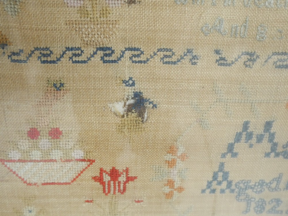 An 1822 hand-embroidered needlework sampler containing verse and decorative motifs, presented inside a glazed birdseye maple frame. View II