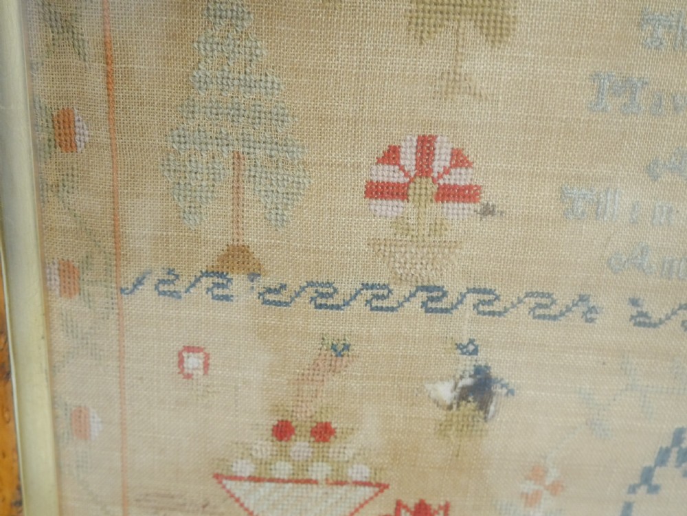 An 1822 hand-embroidered needlework sampler containing verse and decorative motifs, presented inside a glazed birdseye maple frame. View VI