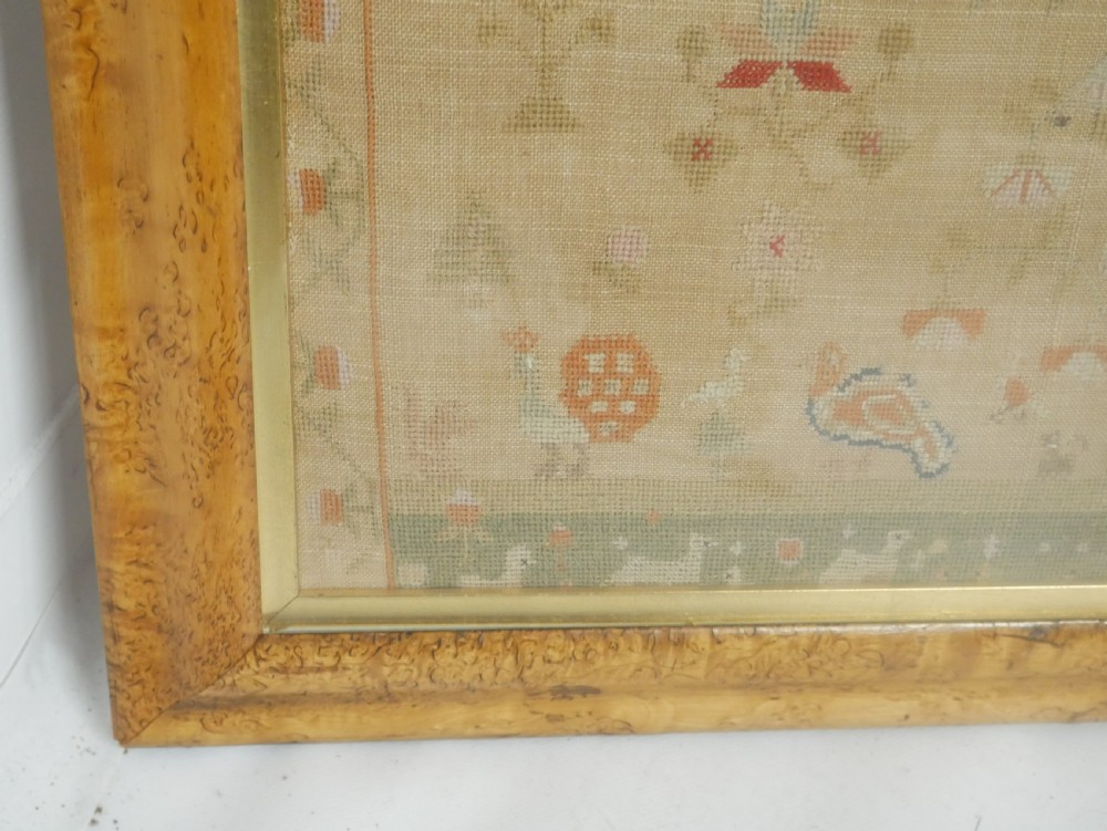 An 1822 hand-embroidered needlework sampler containing verse and decorative motifs, presented inside a glazed birdseye maple frame. View VII