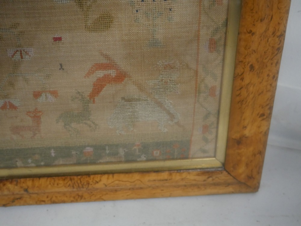 An 1822 hand-embroidered needlework sampler containing verse and decorative motifs, presented inside a glazed birdseye maple frame. View IX