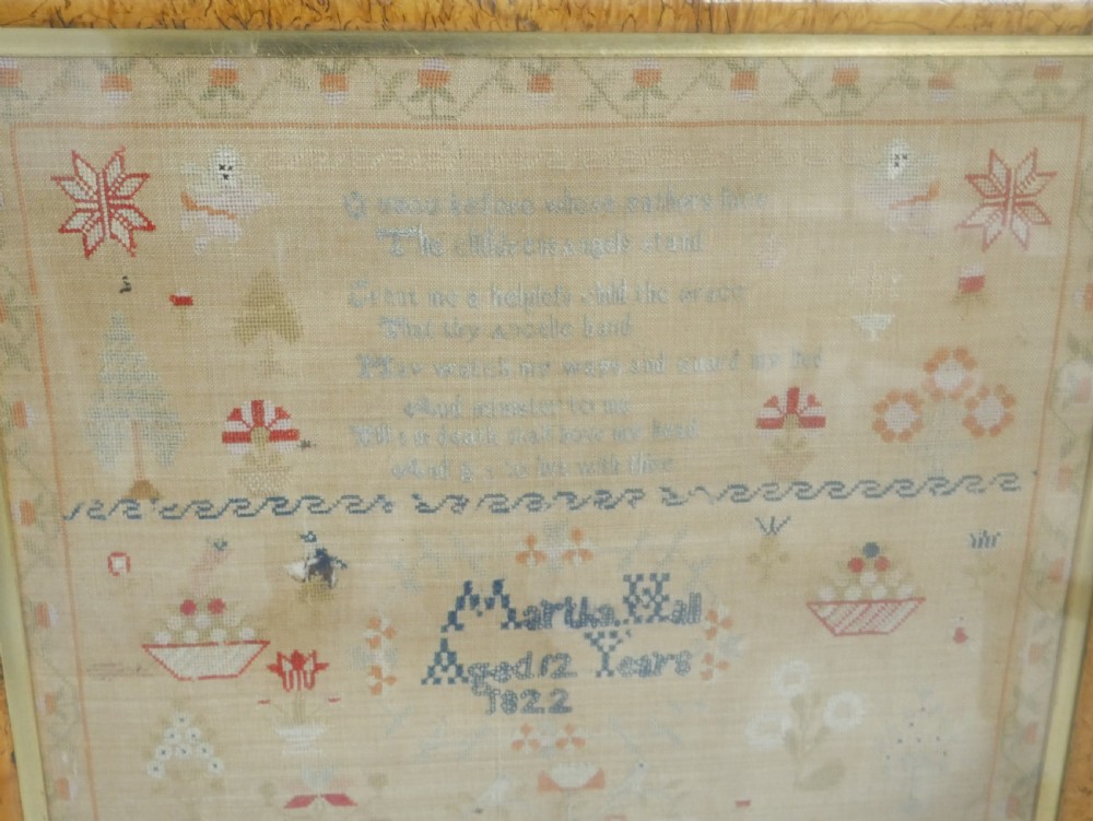 An 1822 hand-embroidered needlework sampler containing verse and decorative motifs, presented inside a glazed birdseye maple frame. View XII