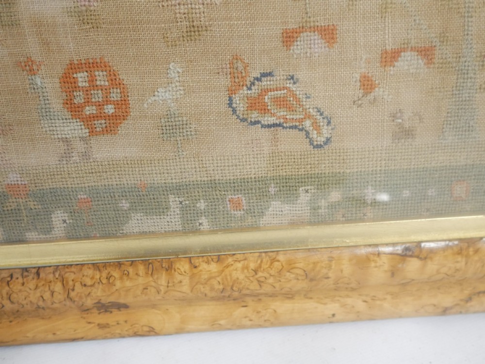 An 1822 hand-embroidered needlework sampler containing verse and decorative motifs, presented inside a glazed birdseye maple frame. View XV