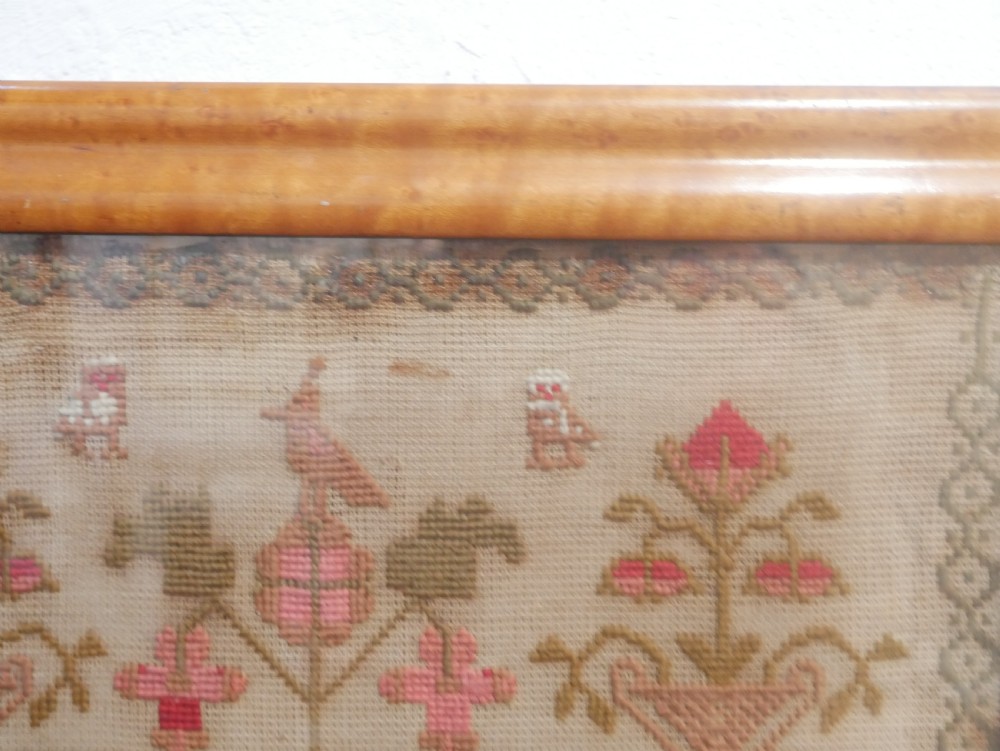 An 1856 Victorian needlework sampler featuring embroidered house, figure, bird, and floral motifs inside a golden maple wood frame. View V